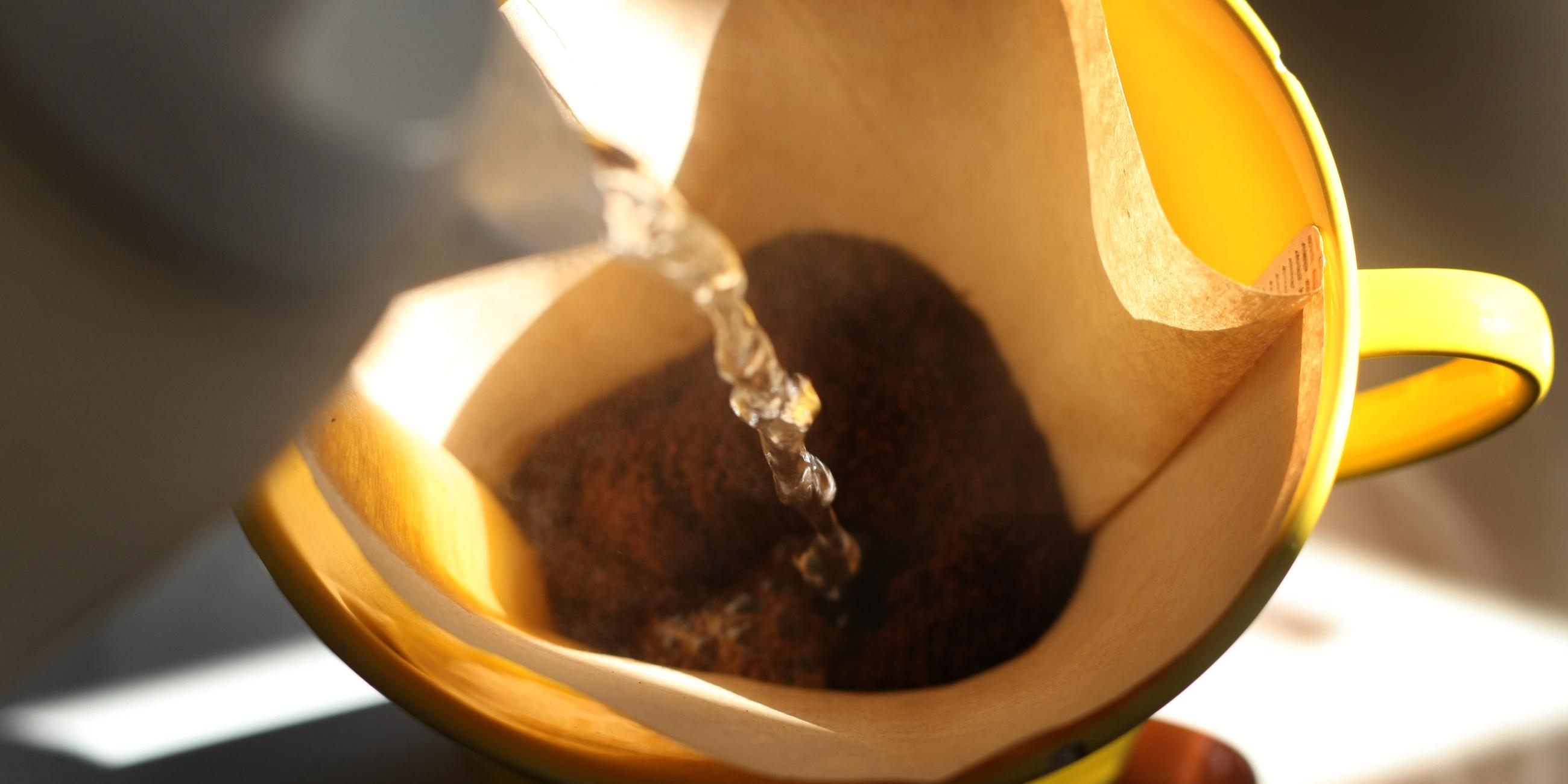 mit kaffee gefuellter filter wird mit heissem wasser uebergossen