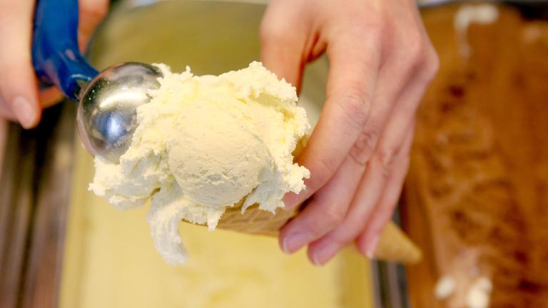 kugel vanilleeis wird auf eine waffel portioniert