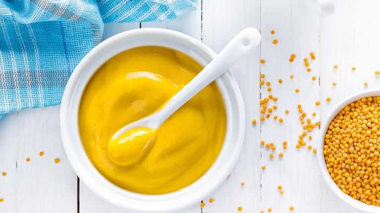 senf in einem topf mit loeffel