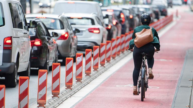 Eine Radfahrerin fährt auf einem Fahrradweg, der parallel zu einer Straße verläuft