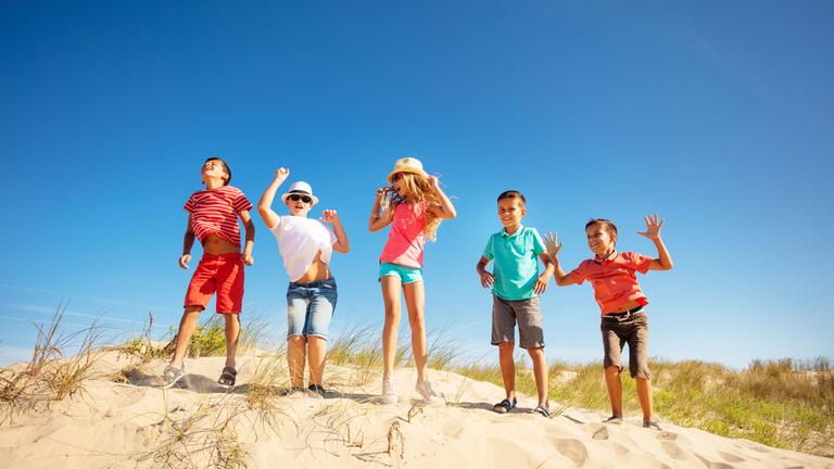 Kinder tanzen auf einer Sanddüne