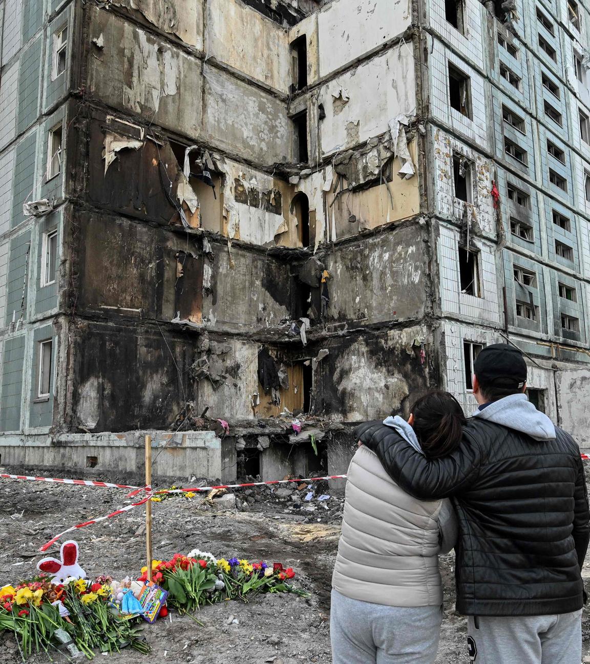 Menschen stehen vor zerstörtem Wohnhaus