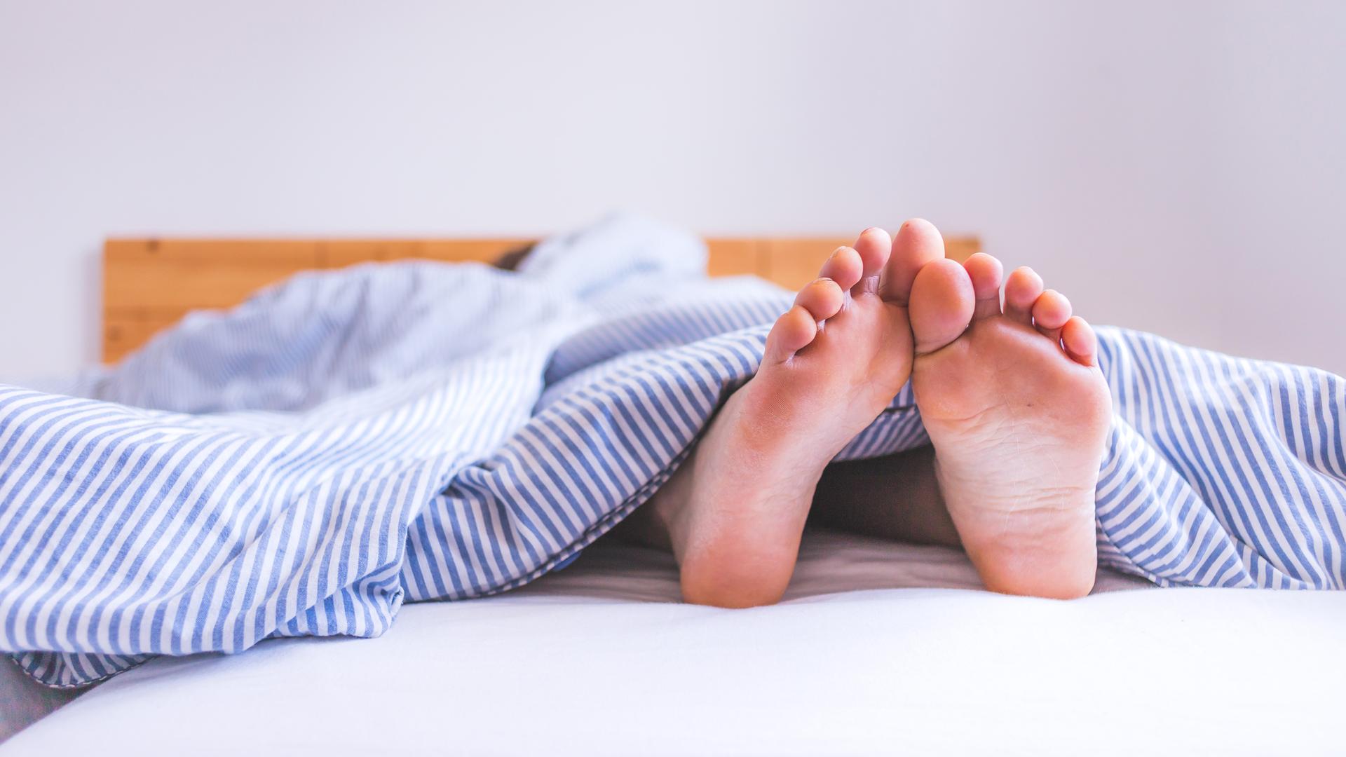 Füße gucken unter Bettdecke hervor