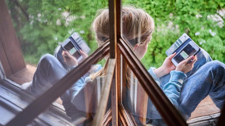 Ein Kind sitzt am Handy.