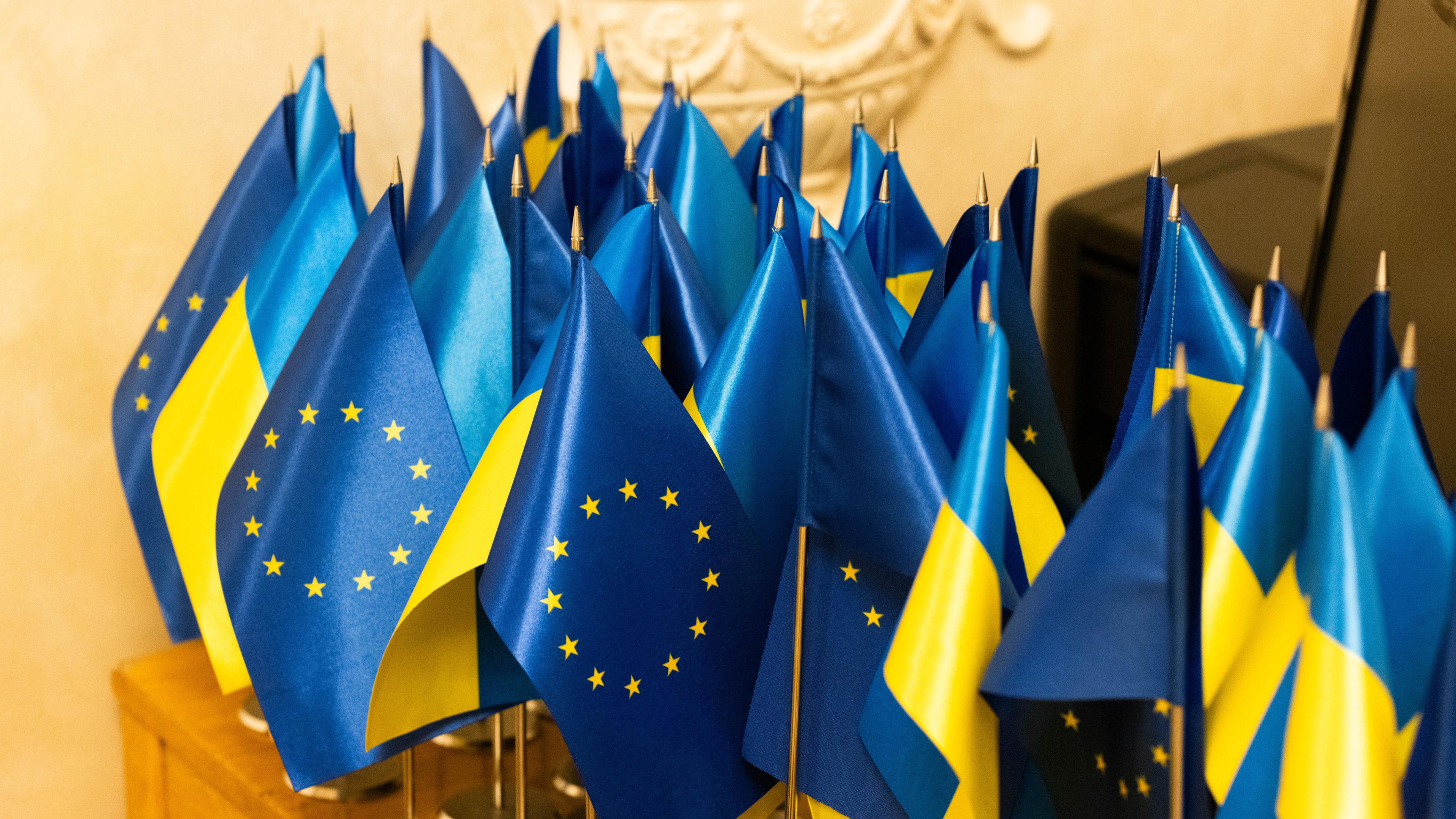Kleine Flaggen der EU und der Ukraine auf einem Tisch