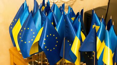 Kleine Flaggen der EU und der Ukraine auf einem Tisch