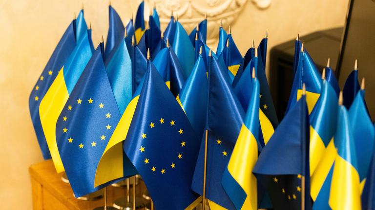 Kleine Flaggen der EU und der Ukraine auf einem Tisch