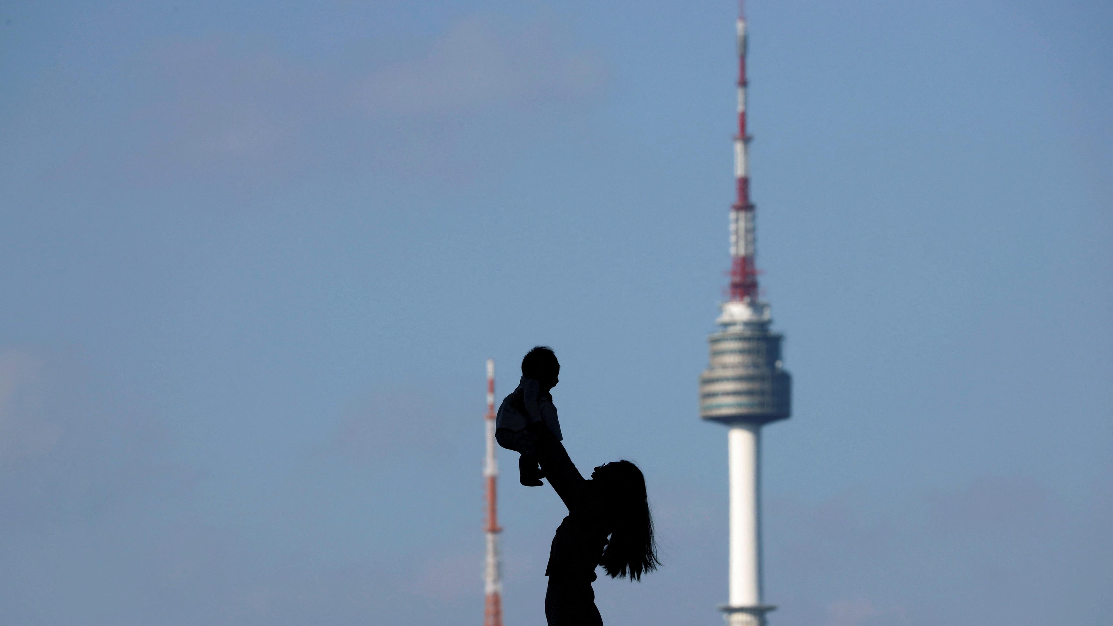 FILE PHOTO: A woman holding up her baby is silhouetted against the backdrop of N Seoul Tower in Seoul