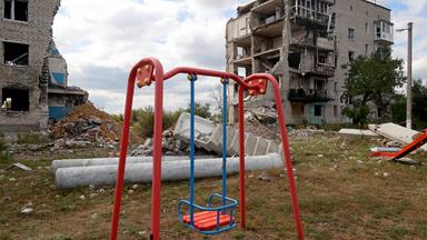 Spielplatz zwischen zerbombten Häusern in der Ukraine