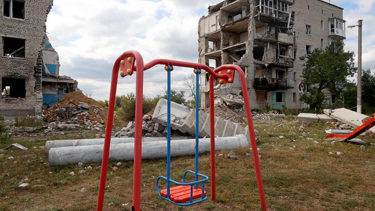 Spielplatz zwischen zerbombten Häusern in der Ukraine