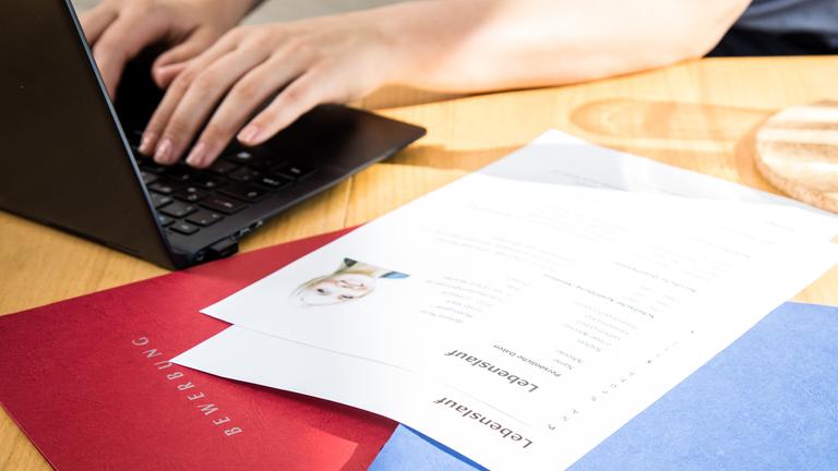 Bewerbungsunterlagen neben Laptop