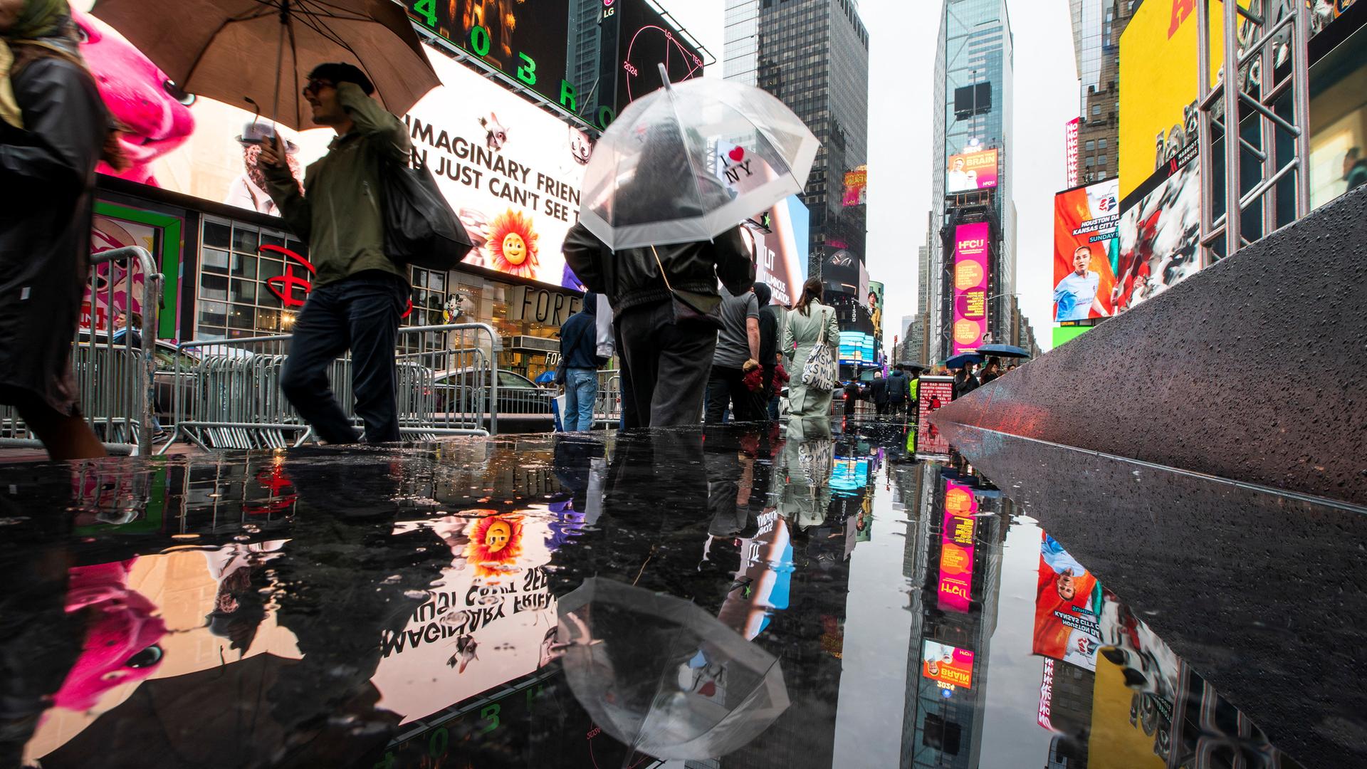 People make their way around Times Square during a rainy day in New York