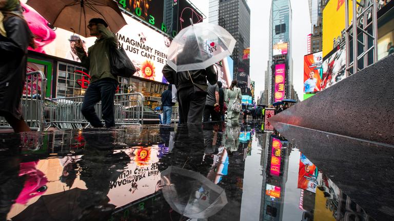 People make their way around Times Square during a rainy day in New York