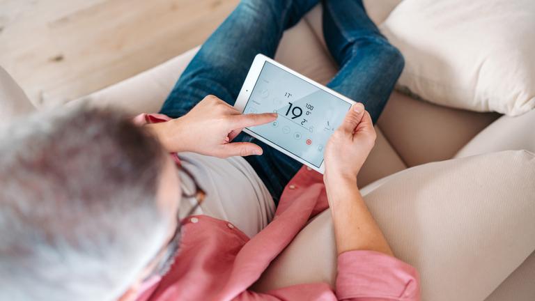 Man using smart thermostat, adjusting or lowering heating temperatures at his home. Concept of sustainable, efficient, and smart
