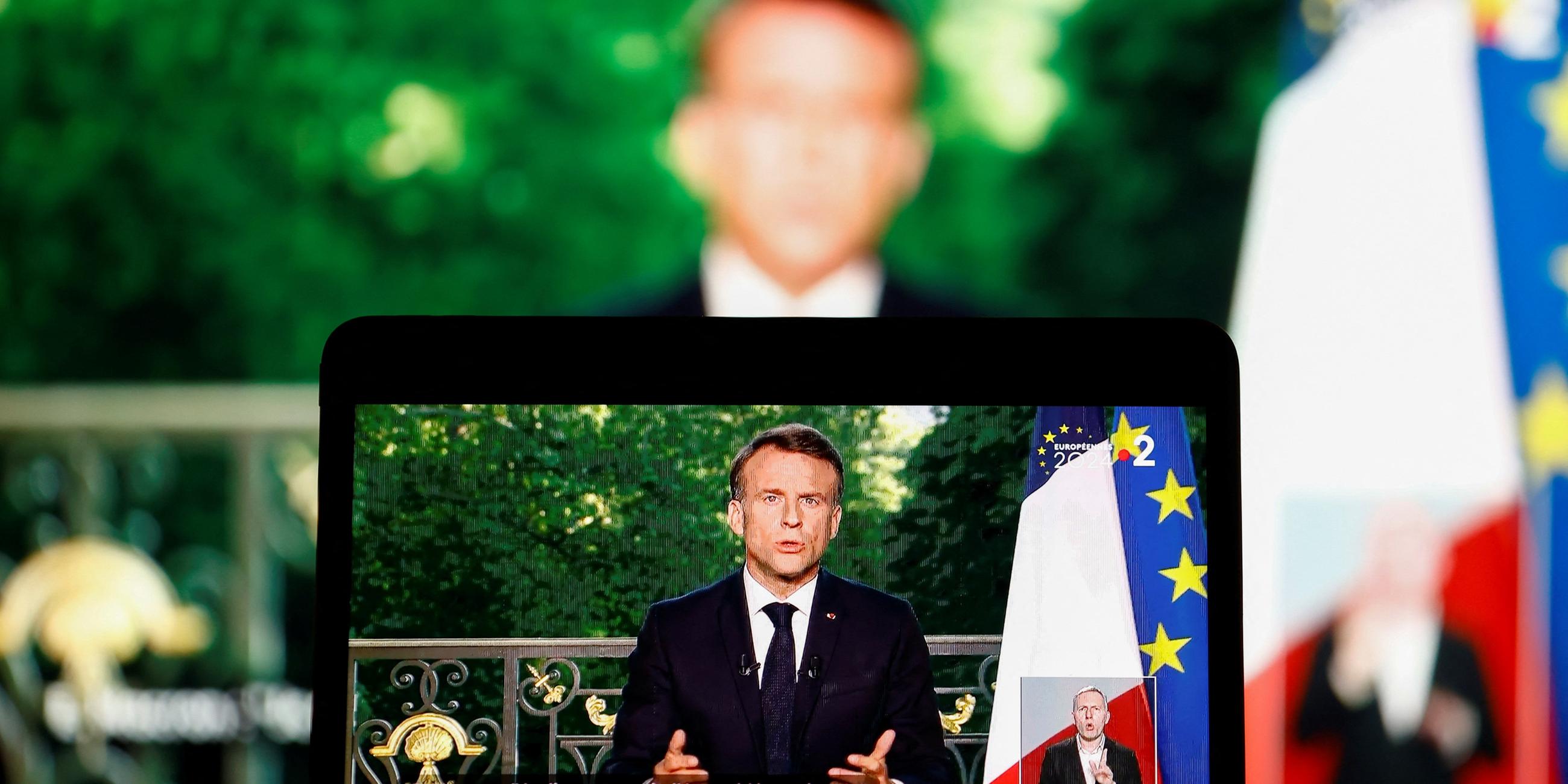 French President Emmanuel Macron appears on a screen as he delivers a speech following results after the polls closed in the Eur