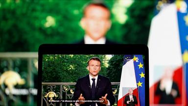 French President Emmanuel Macron appears on a screen as he delivers a speech following results after the polls closed in the Eur