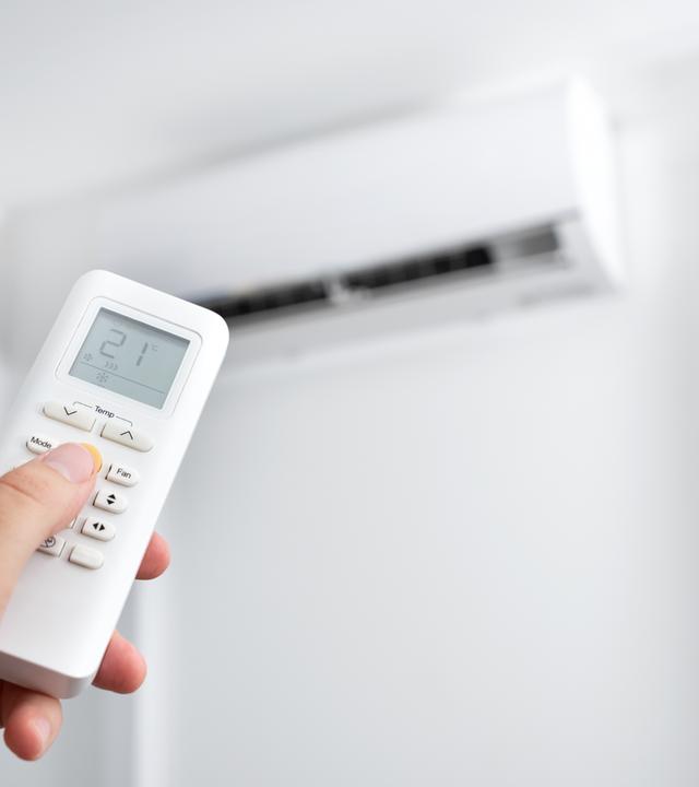 Hand hält die Fernbedienung für eine Klimaanlage