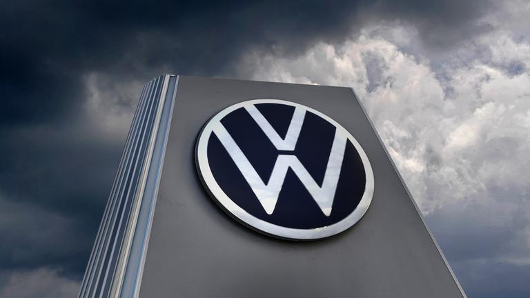 VW-Schild vor dunklen Wolken - Fotomontage Symbol Autokrise