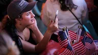 Frau, die die US-Wahlergebnisse auf dem Handy verfolgt