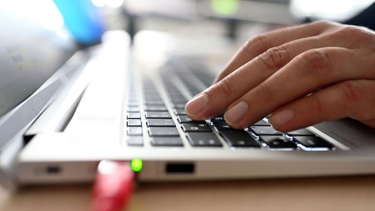 Mann tippt an einem Laptop