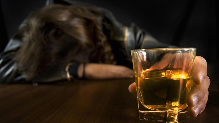 Verzweifelte alkoholisierte Person mit Whiskey-Glas