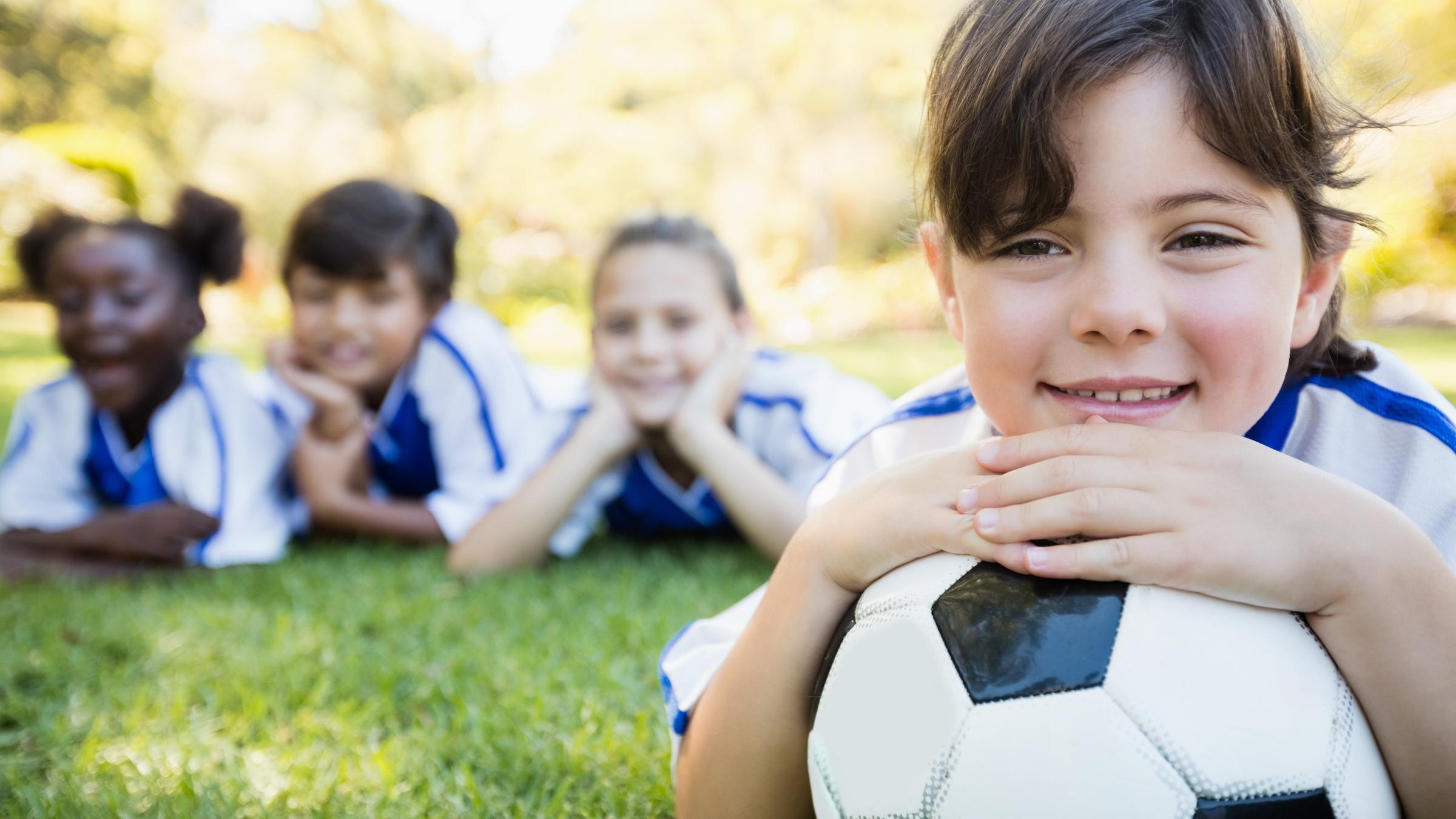 Nahaufnahme eines Mädchens, das mit seiner Fußballmannschaft auf dem Boden liegt