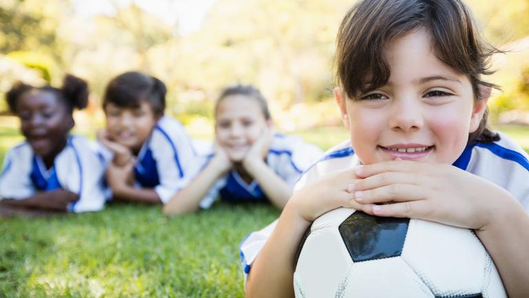 Nahaufnahme eines Mädchens, das mit seiner Fußballmannschaft auf dem Boden liegt