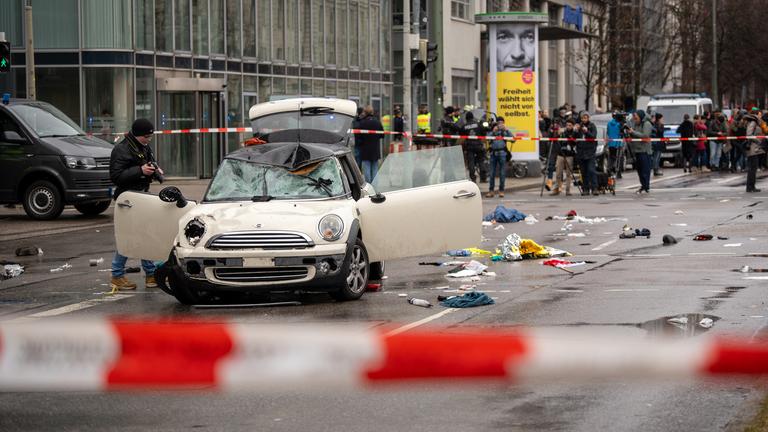 Ein Mann steuert Auto in Demo in München