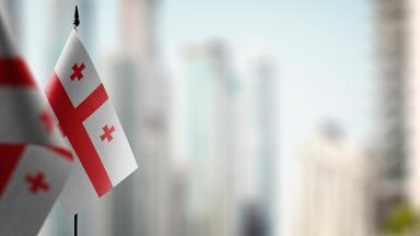 Kleine Flaggen von Georgien auf einem abstrakten unscharfen Hintergrund