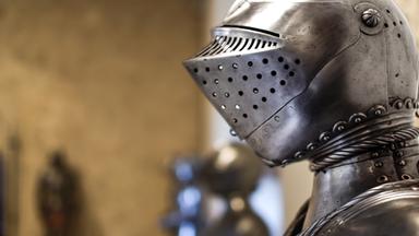 Nahaufnahme des mittelalterlichen glänzenden Helms mit Details und Rüstungen im Hintergrund