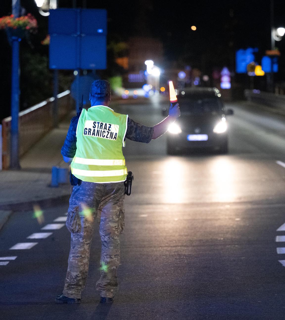 Polnischer Grenzer hält ein Auto an deutscher Grenze an.