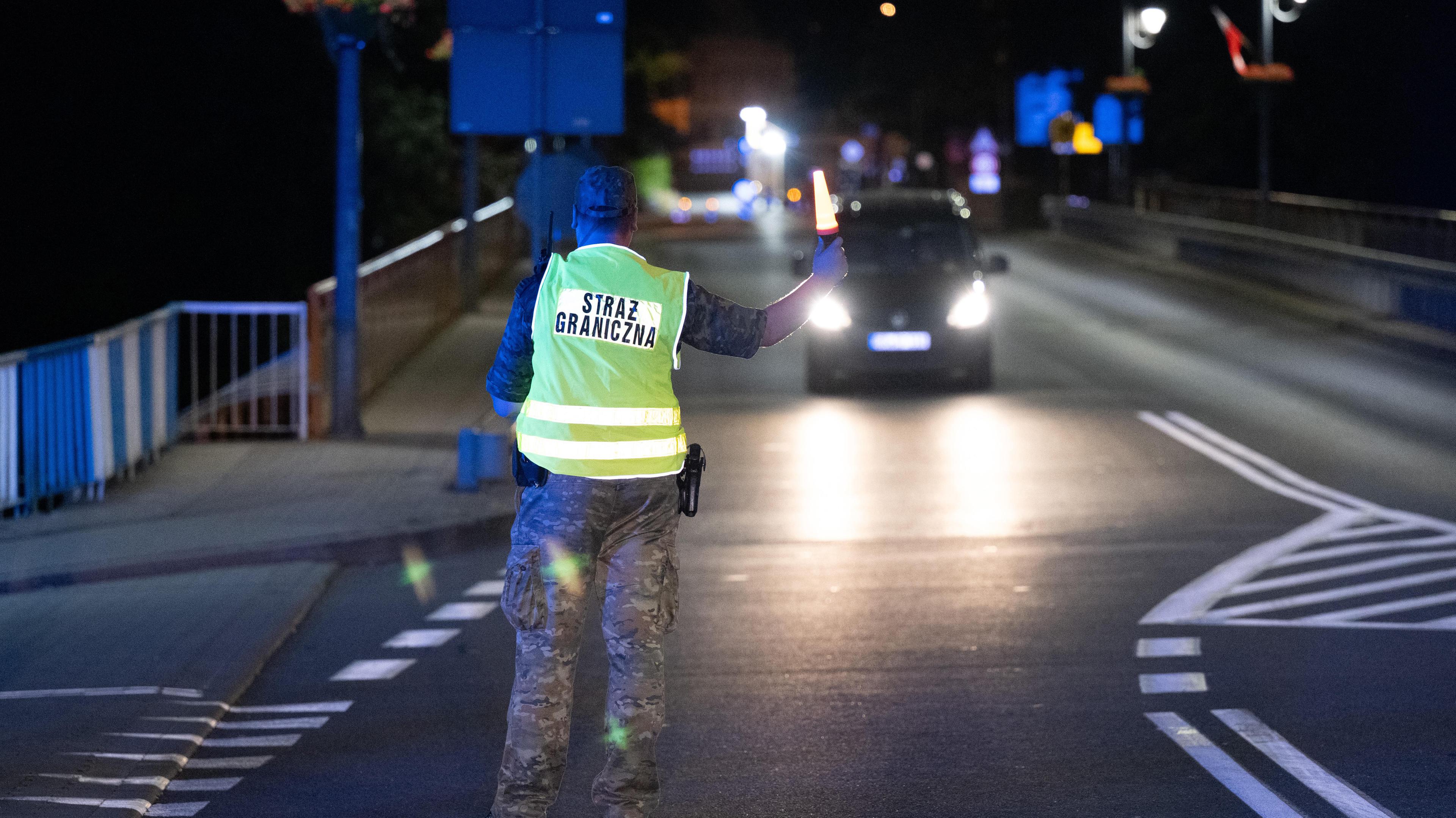 Polnischer Grenzer hält ein Auto an deutscher Grenze an.
