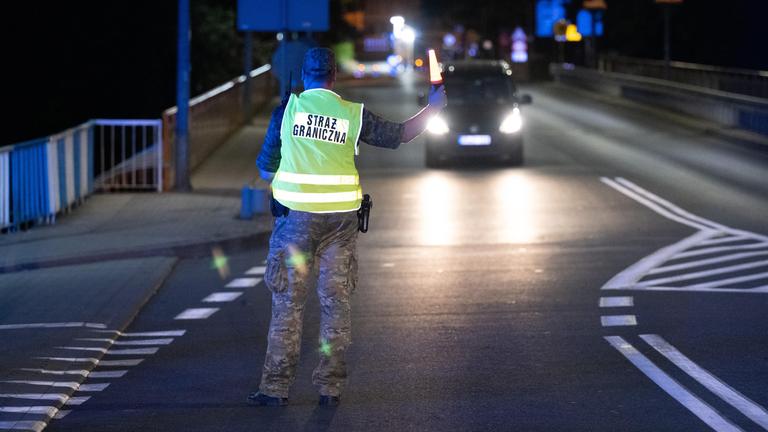 Polnischer Grenzer hält ein Auto an deutscher Grenze an.