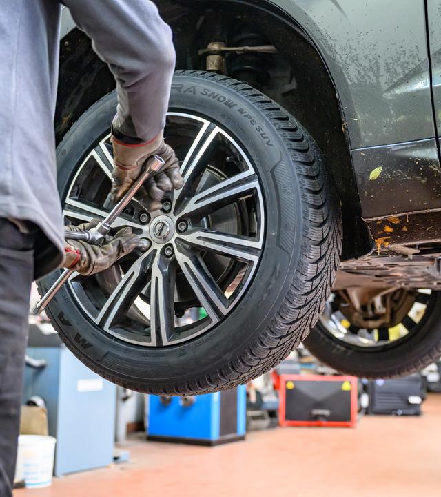 Winterreifen wird in Werkstatt an Auto montiert