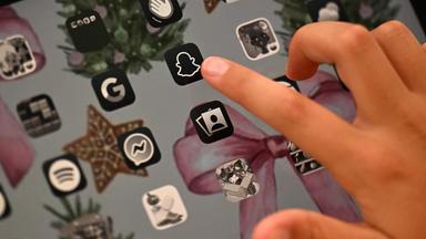 Kind zeigt mit Finger auf Symbol von Snapchat
