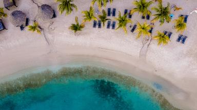 Ruhiger Strandblick in Willemstad, Curaçao, mit ruhigem türkisfarbenem Wasser und sich im Wind wiegenden Palmen