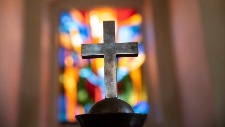 Kreuz vor buntem Kirchenfenster