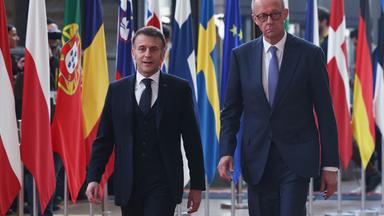 Der deutsche Bundeskanzler Friedrich Merz  und der französische Präsident Emmanuel Macron, laufen neben Flaggen der Europäischen Staaten vorbei