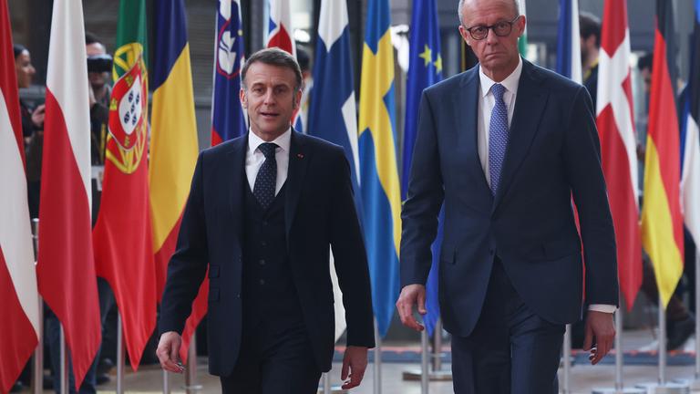 Der deutsche Bundeskanzler Friedrich Merz  und der französische Präsident Emmanuel Macron, laufen neben Flaggen der Europäischen Staaten vorbei