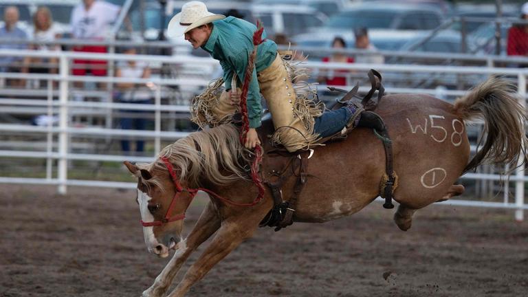 Ein Mann reitet beim Rodeo in Sutherland, Nebraska, auf einem Pferd. 
