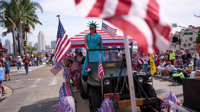 Zuschauer verfolgen eine Parade zum Unabhängigkeitstag in Coronado, Kalifornien. Eine Frau, die als Freiheitsstatue verkleidet ist, fährt auf einem Festwagen mit.