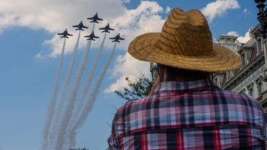 Ein Mann mit Hut beobachtet, wie sechs Kampfjets in Formation über die US-Hauptstadt hinwegfliegen. 