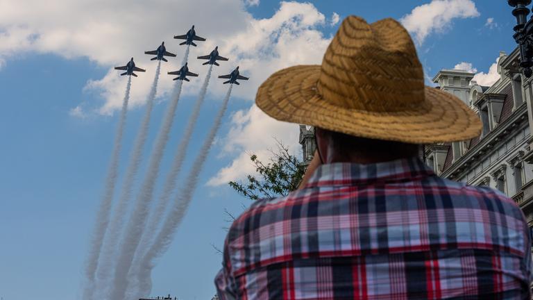 Ein Mann mit Hut beobachtet, wie sechs Kampfjets in Formation über die US-Hauptstadt hinwegfliegen. 