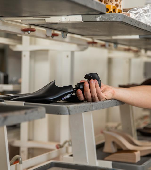 A shoe maker holding a shoe last inside the manufacturing factory   xkwx shoe fashion production mad