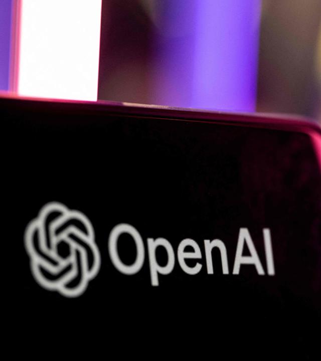 OpenAI Logo auf einem Bildschirm. Im Hintergrund leuchten magenta Lichtstangen.