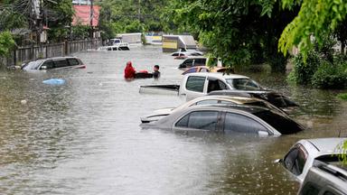 Eine Straße in Bangkok, in der das Wasser so hoch steht, dass man nur noch die obrere Hälfte der Autos sehen kann.