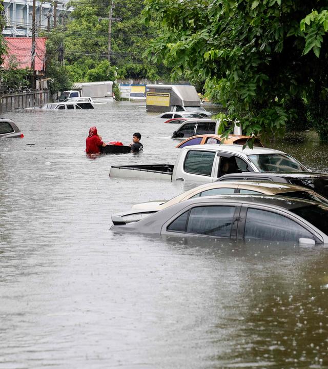 Eine Straße in Bangkok, in der das Wasser so hoch steht, dass man nur noch die obrere Hälfte der Autos sehen kann.
