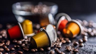 Colorful Coffee Capsules and Espresso Pods Scattered Among Roast Coffee Beans on Dark Surface