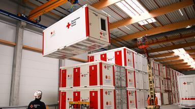 Container des DRK werden mit einem Krahn bewegt.