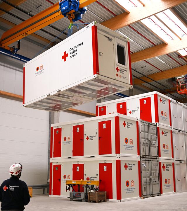 Container des DRK werden mit einem Krahn bewegt.